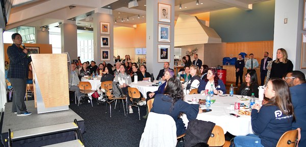 Nichol Whiteman, LA Dodgers Foundation CEO holding a microphone and speaking to a large audience in the Stadium Club 