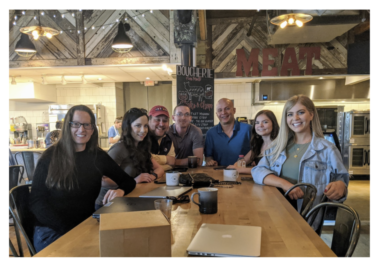 A group of 7 smiling faces at a coffee shop.