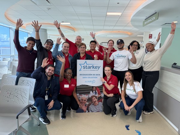 Group of smiling people with red t-shirts with Starkey Hearing Foundation Logo on them 
